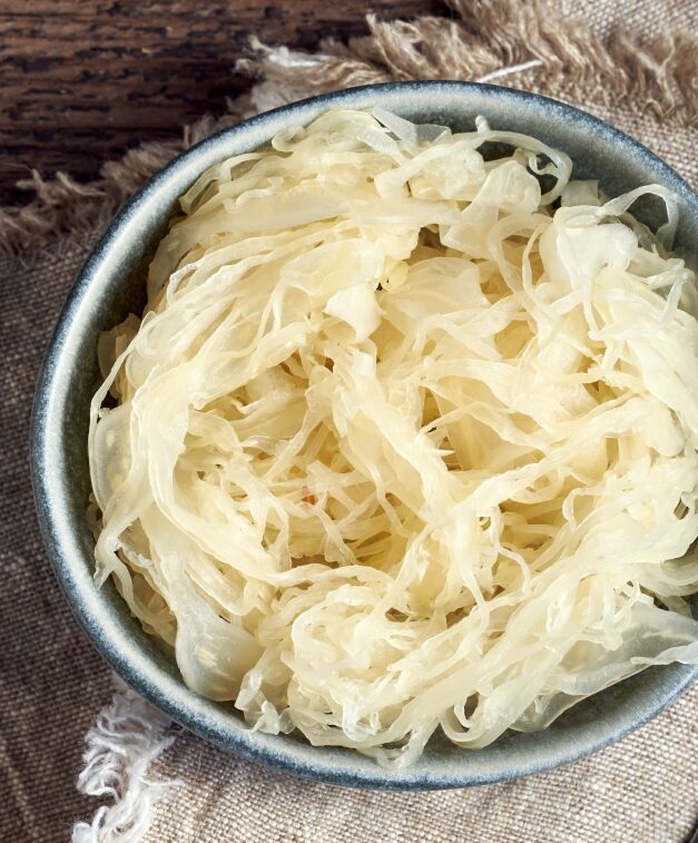 Bol argenté de choucroute disposé sur une serviette beige sur une table en bois