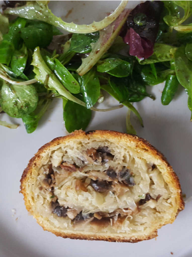 Feuilleté d'escargot à la choucroute disposé dans une assiette avec une salade verte