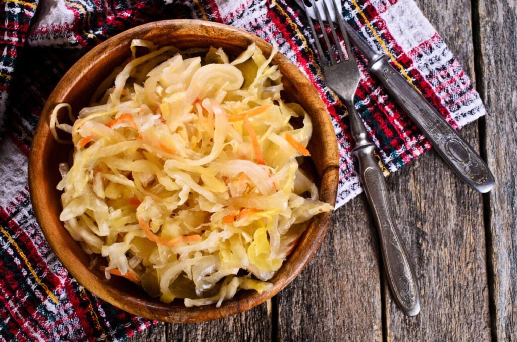 Salade de choucroute dans un bol en bois disposé sur une table en bois avec une serviette et des couverts